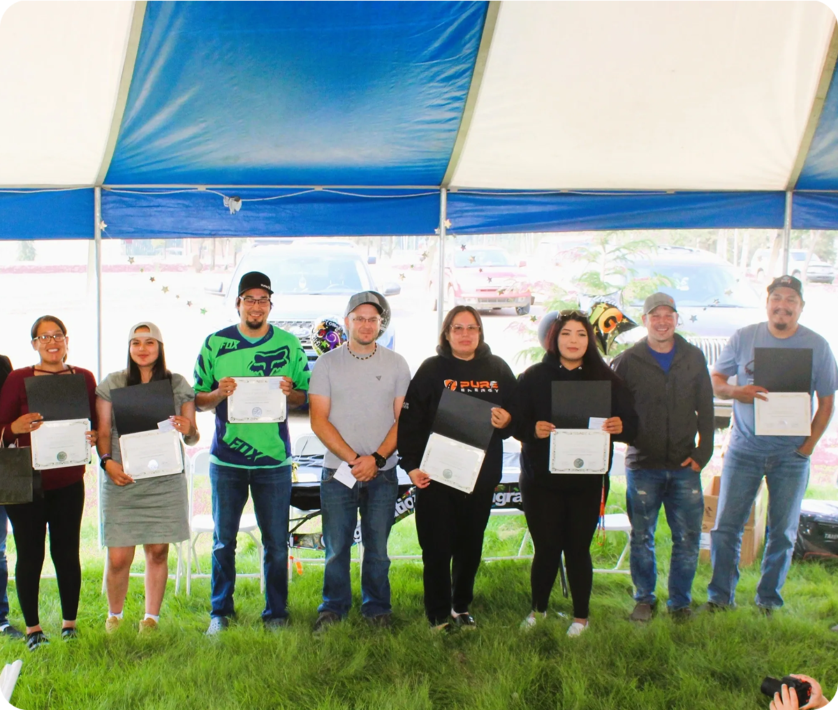 Group holding certificates under a tent