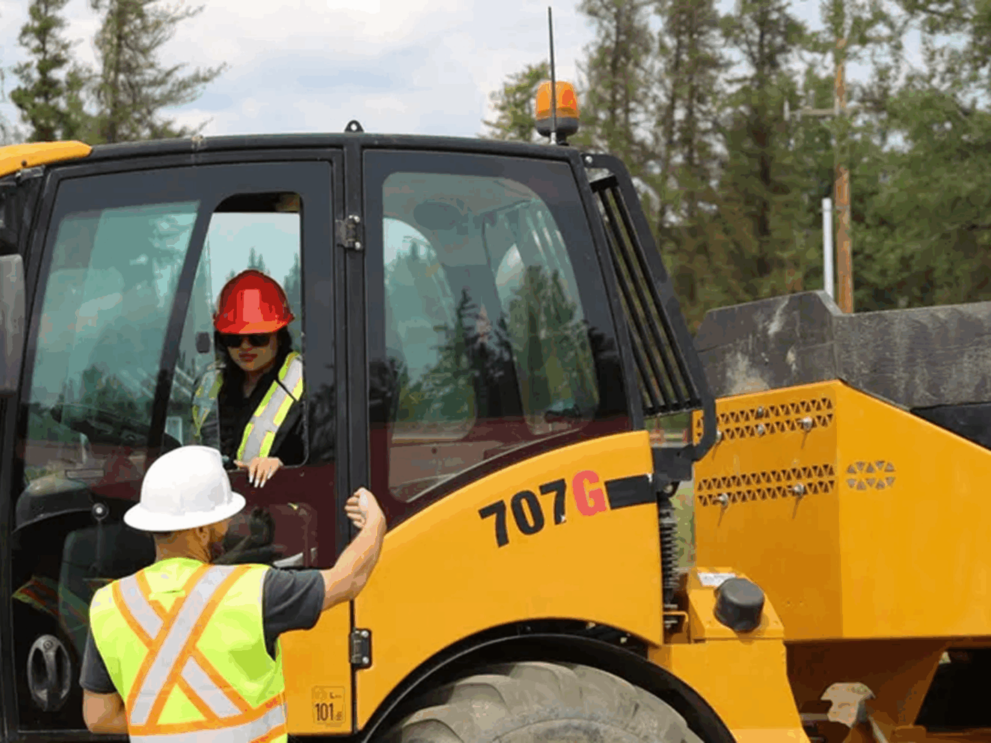 Construction workers communicating near heavy machinery