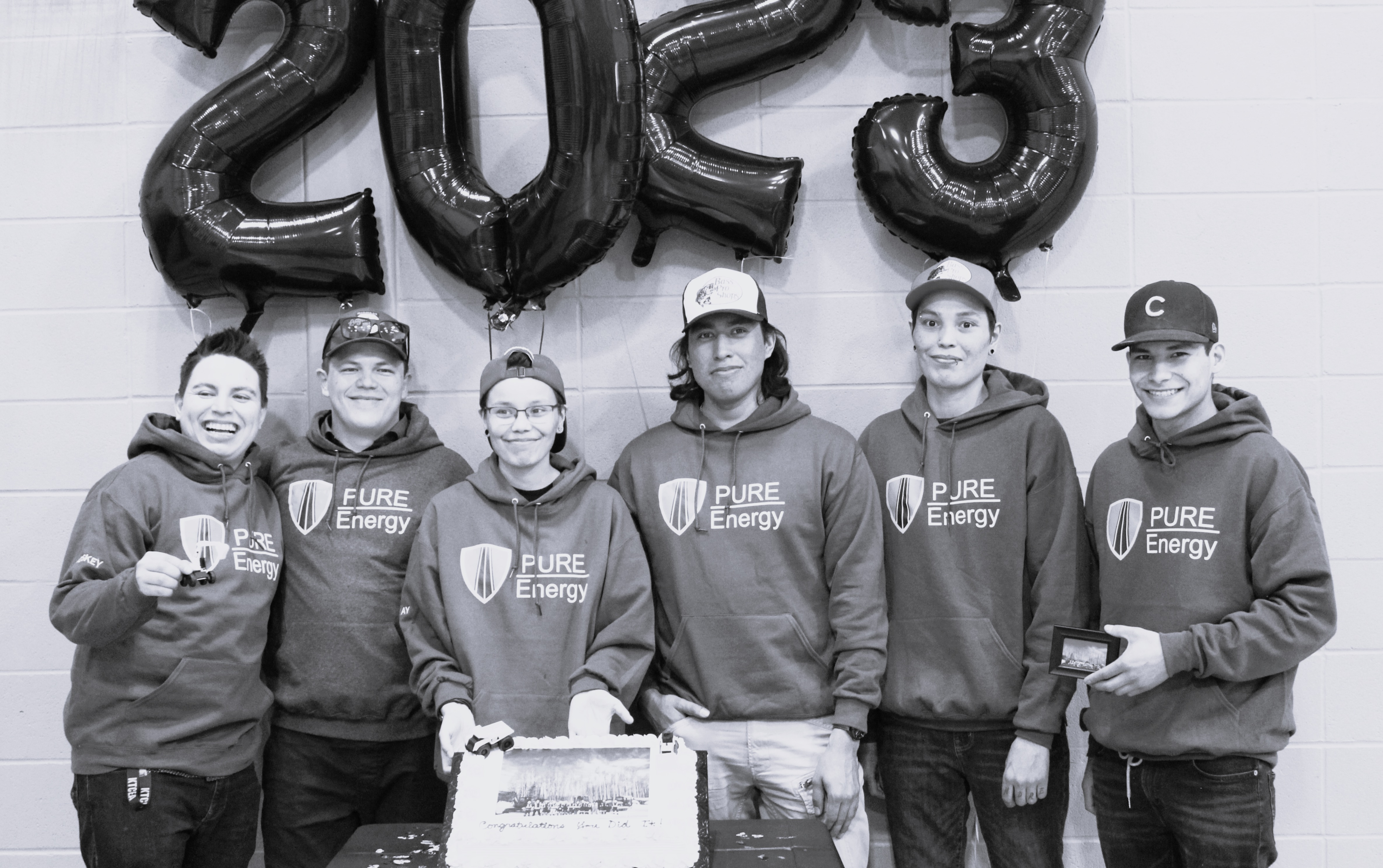 Group of five people posing together in matching sweatshirts for an event in 2023.