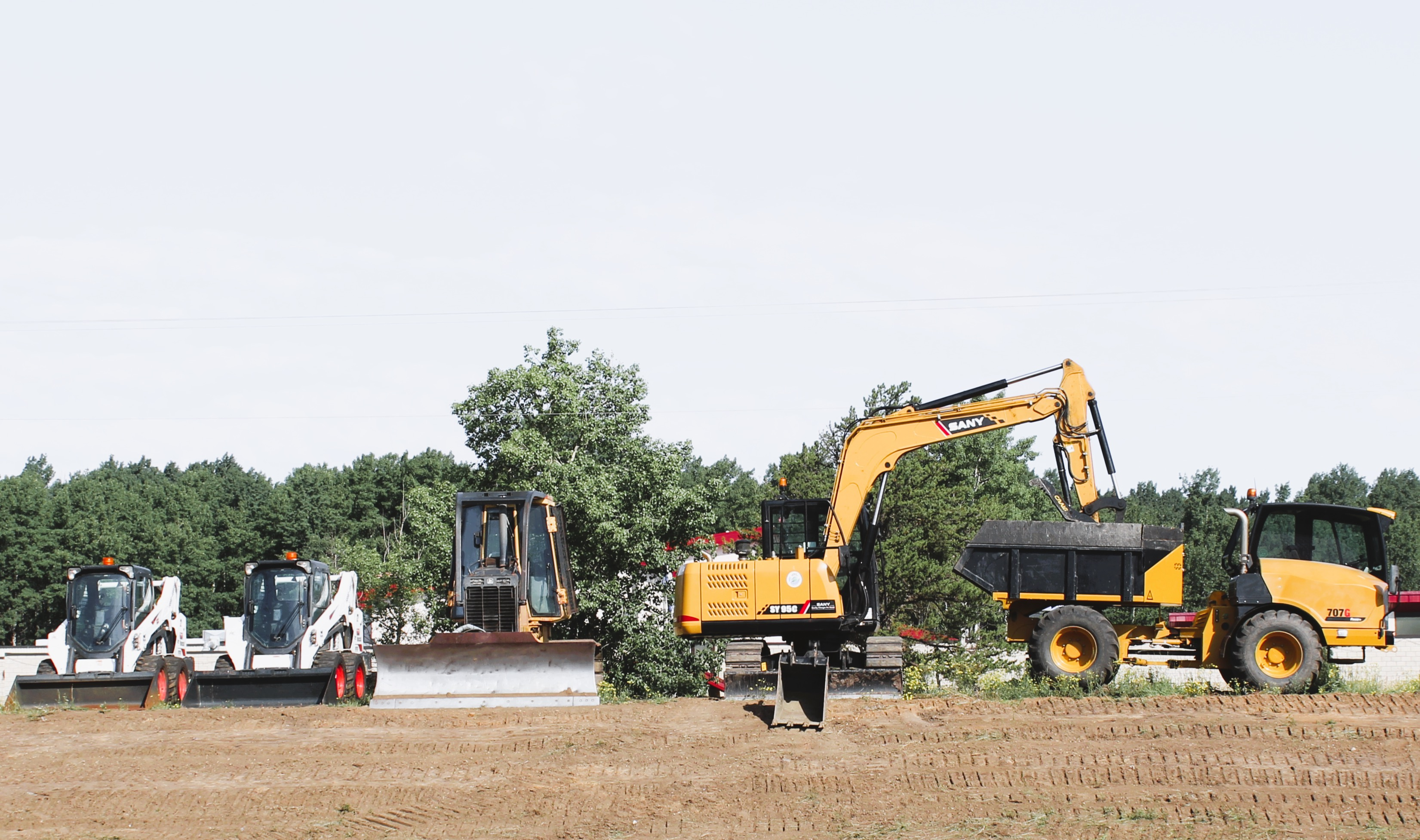 Construction site with excavators preparing the ground near trees.