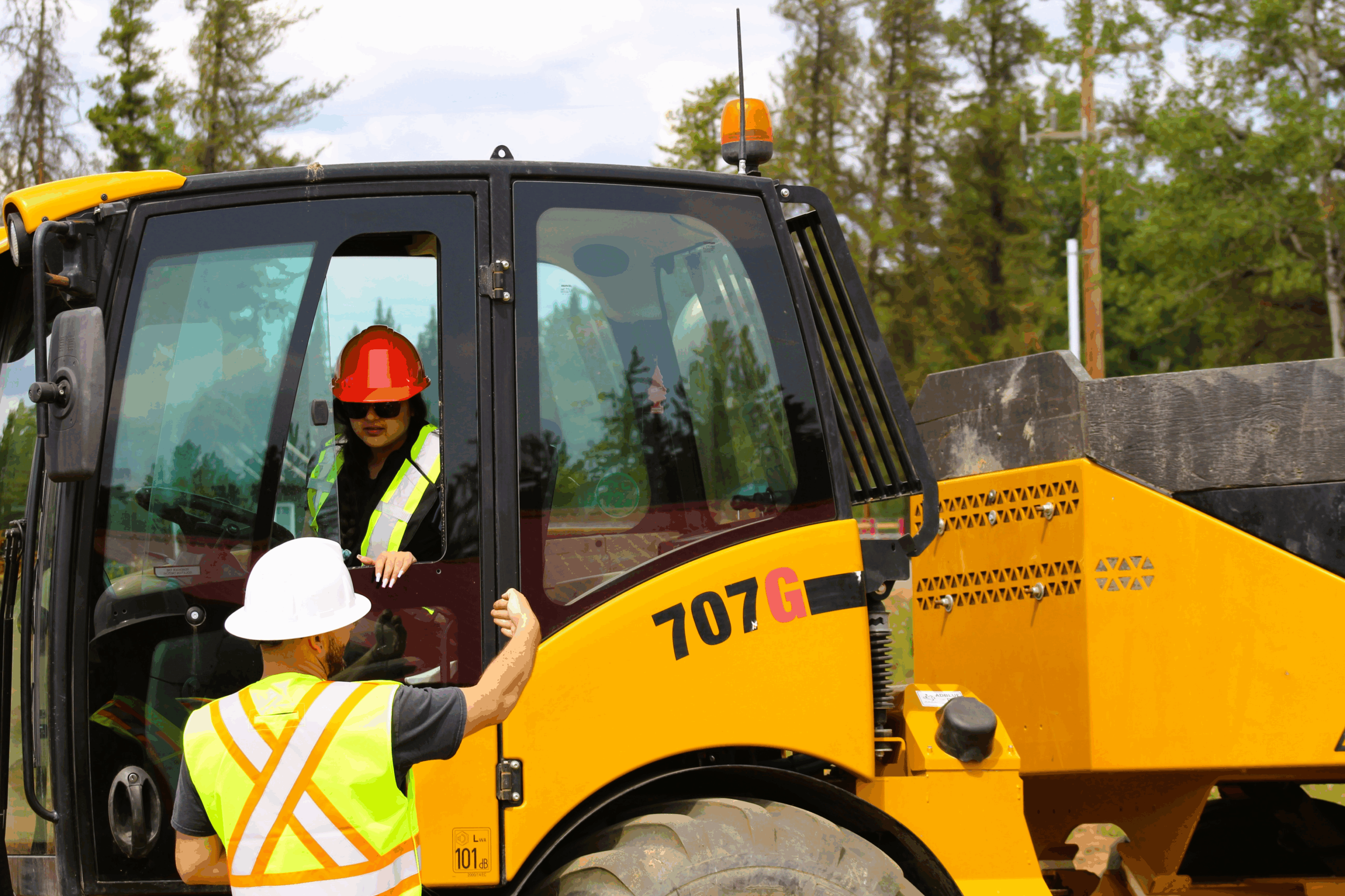 Two construction workers operating heavy machinery outdoors.