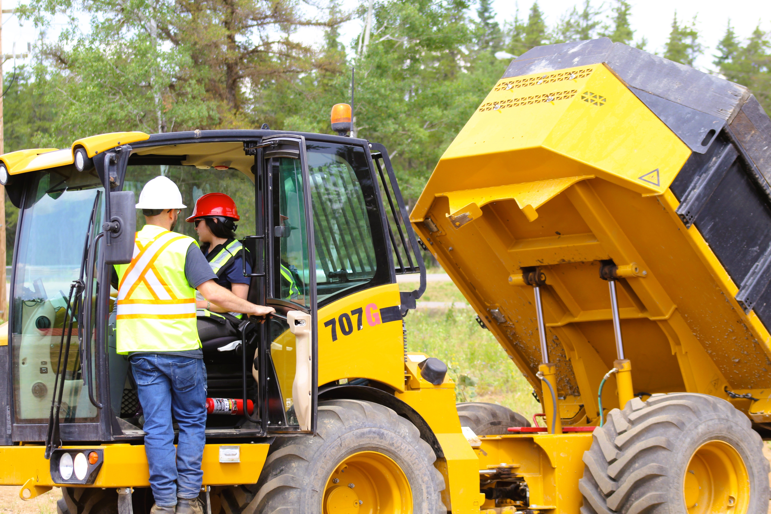 Construction workers operating heavy machinery at a site.