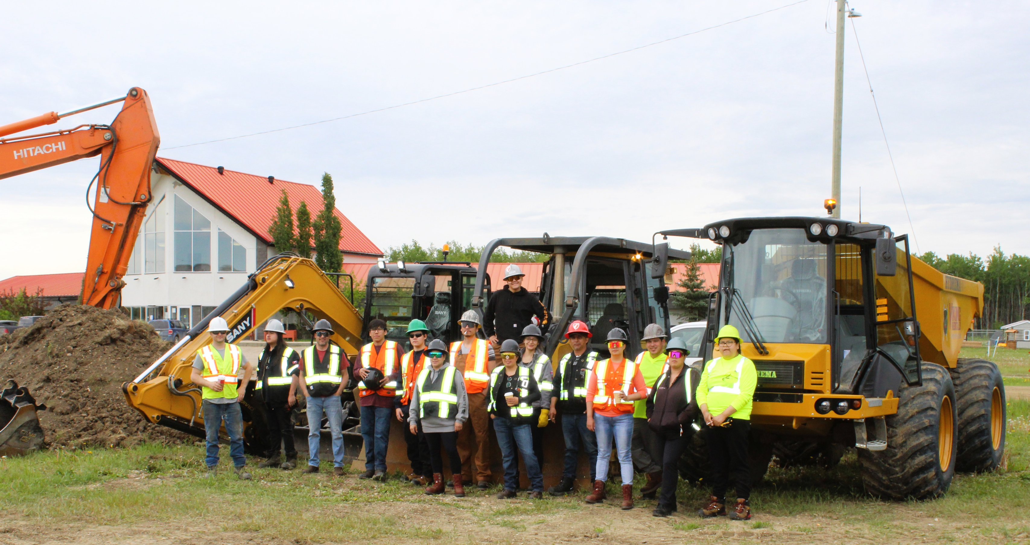 Group of workers in safety gear posing with construction equipment.