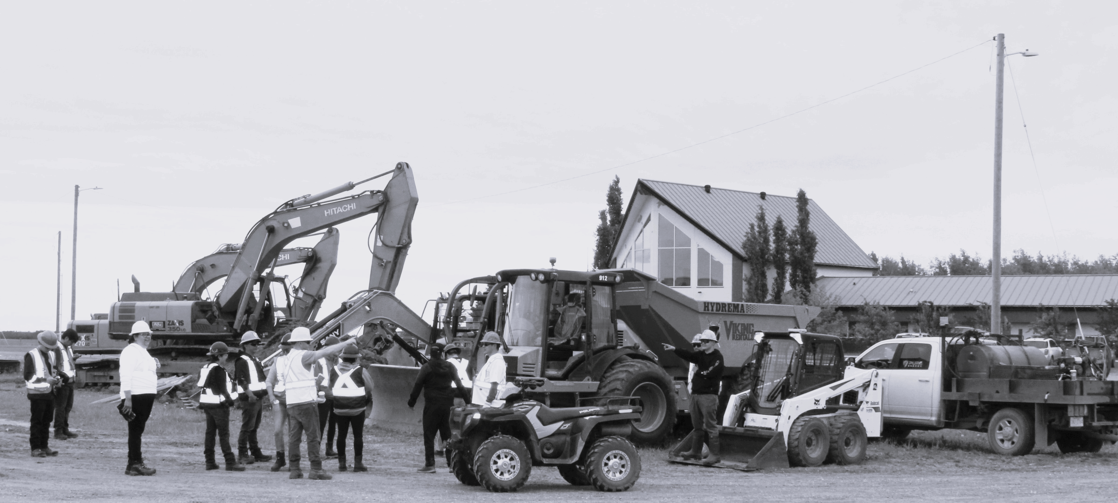 Construction workers and machinery at a residential site with a house in the background.