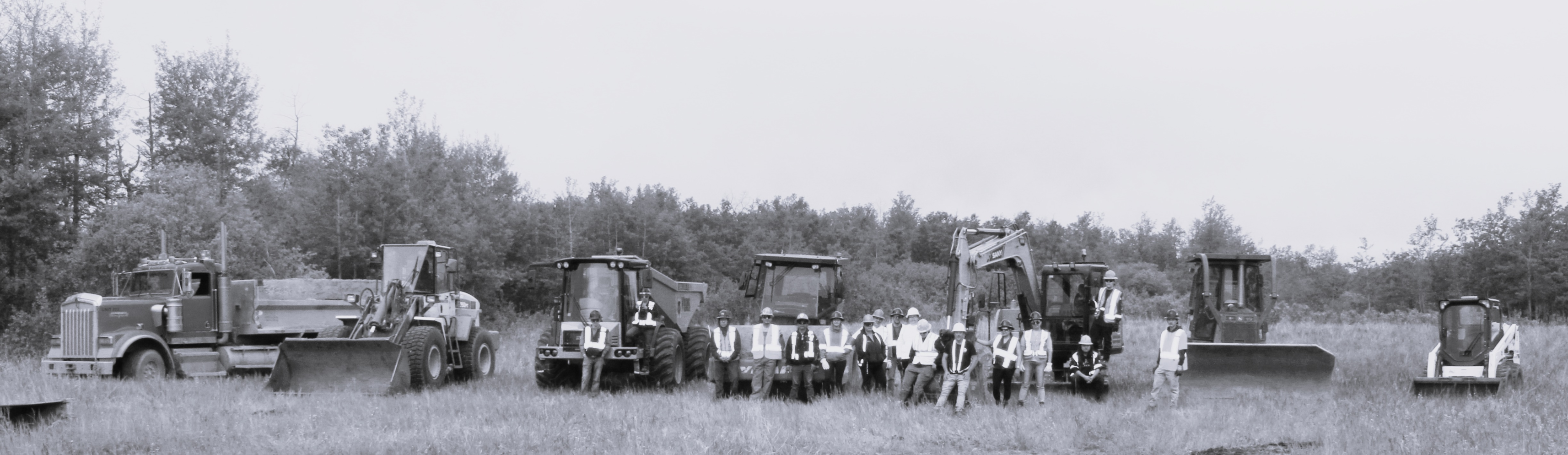 Group of men standing in front of tractors in a field.