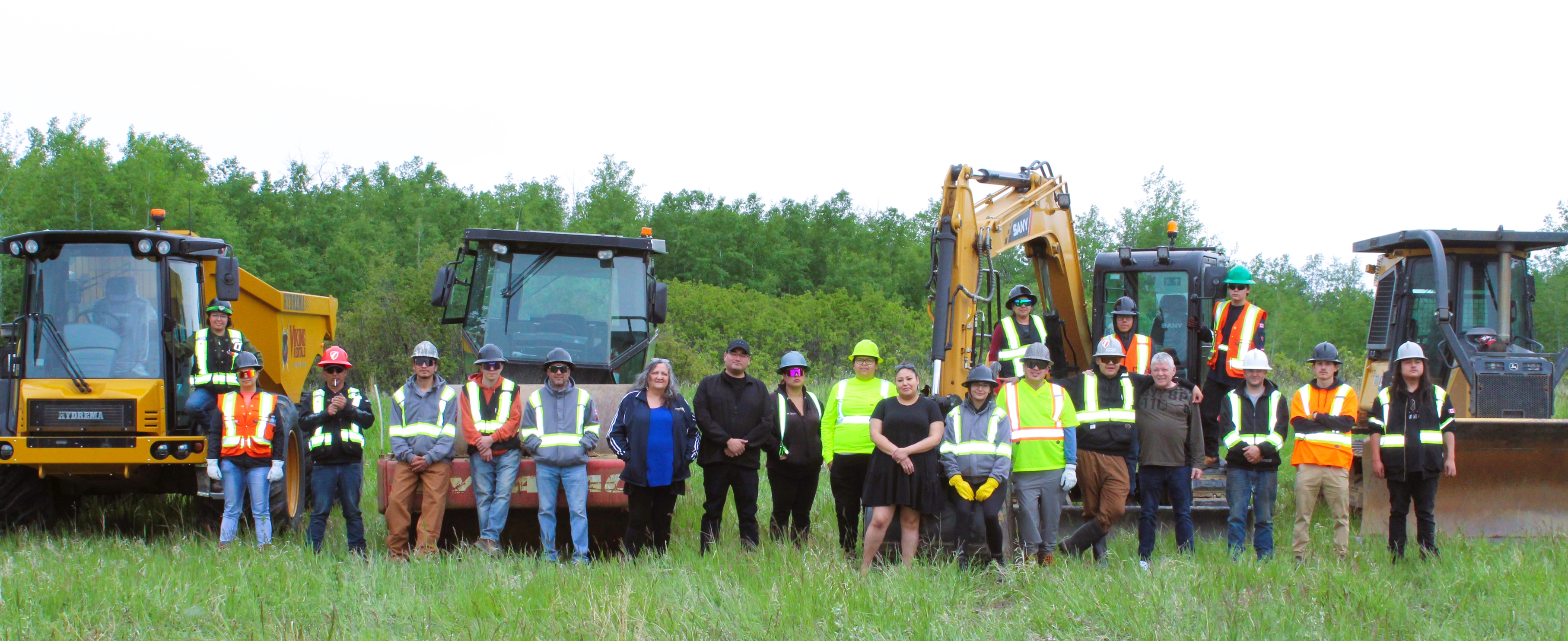 Group of workers standing in a field near construction vehicles.