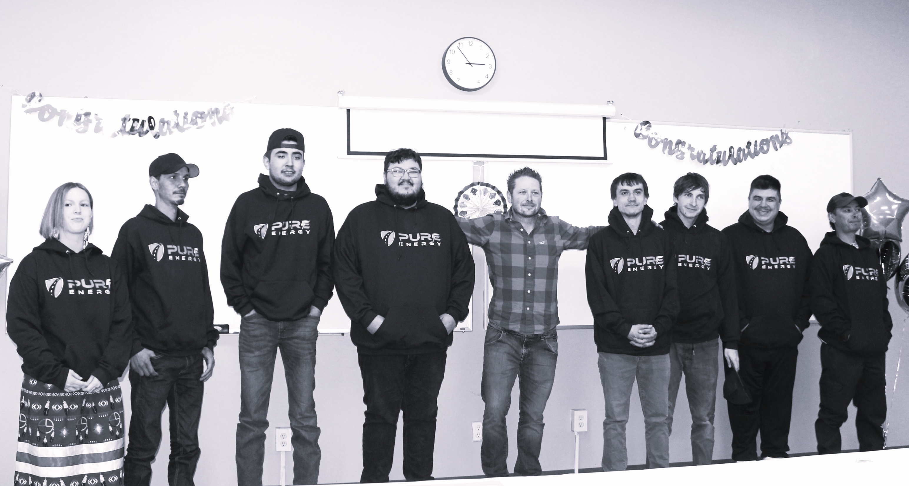 A group of six young men standing indoors, some wearing matching hoodies.
