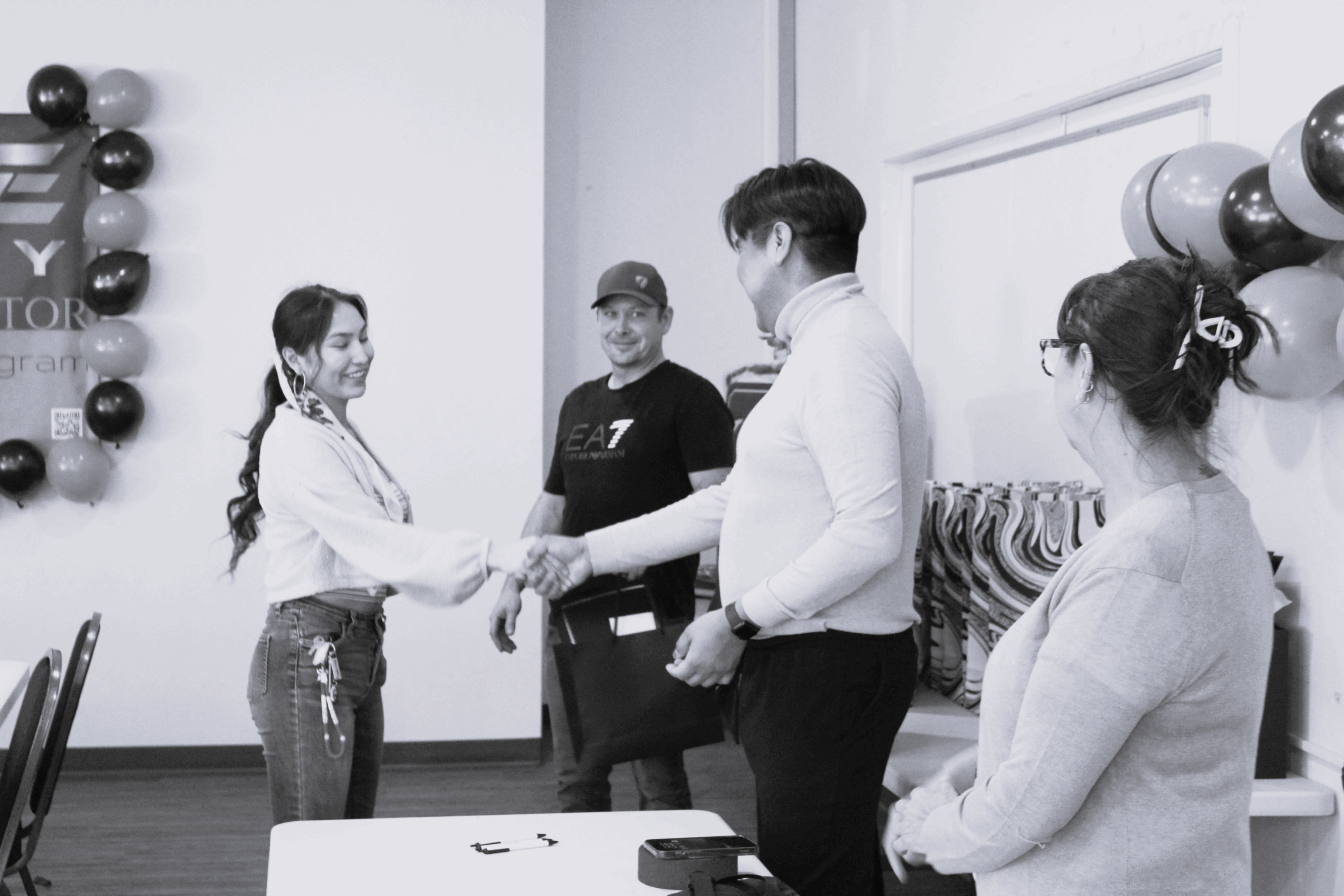 Two people shaking hands while others watch in a casual meeting.