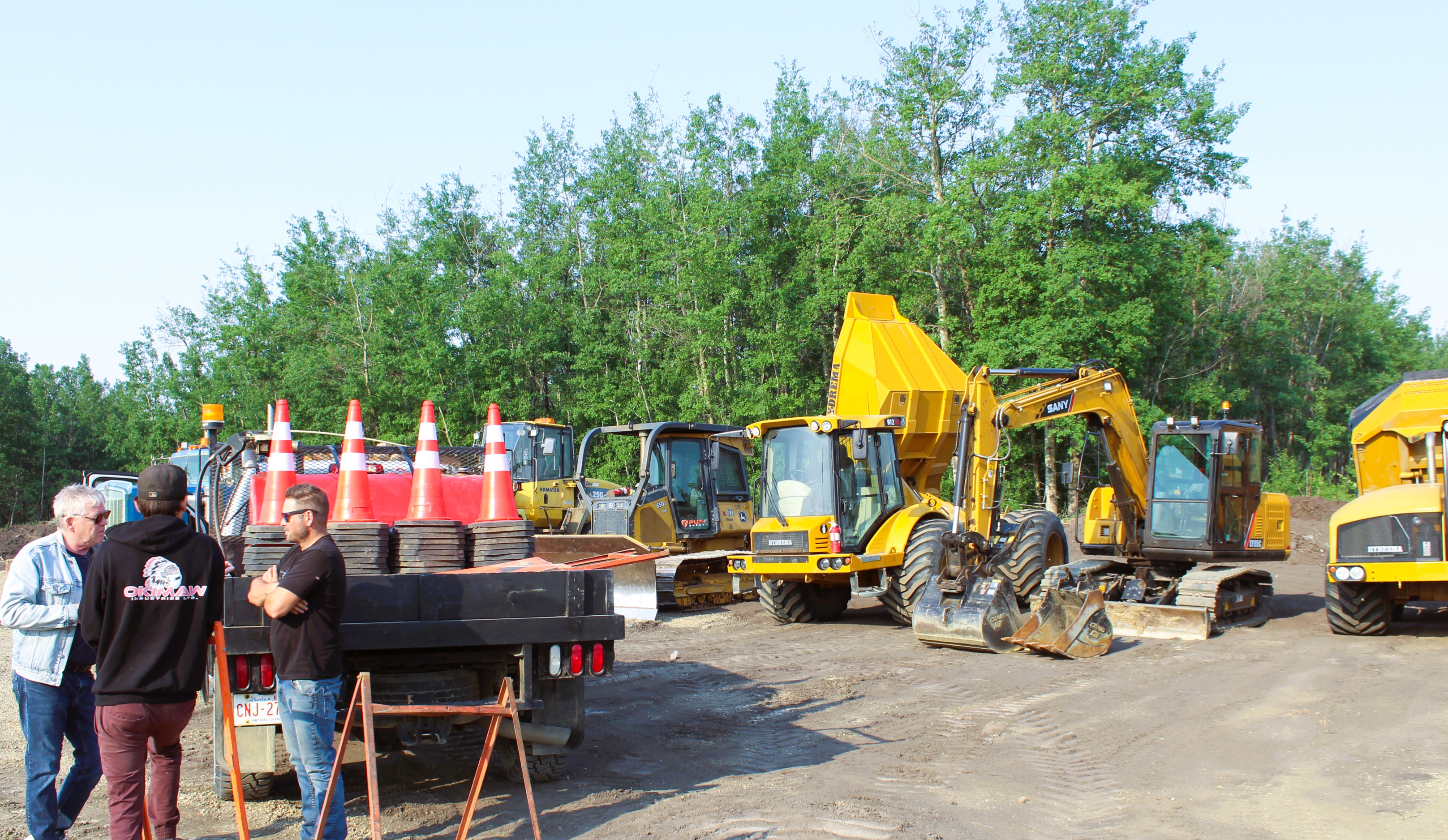 Construction site with excavators and trucks under clear skies.